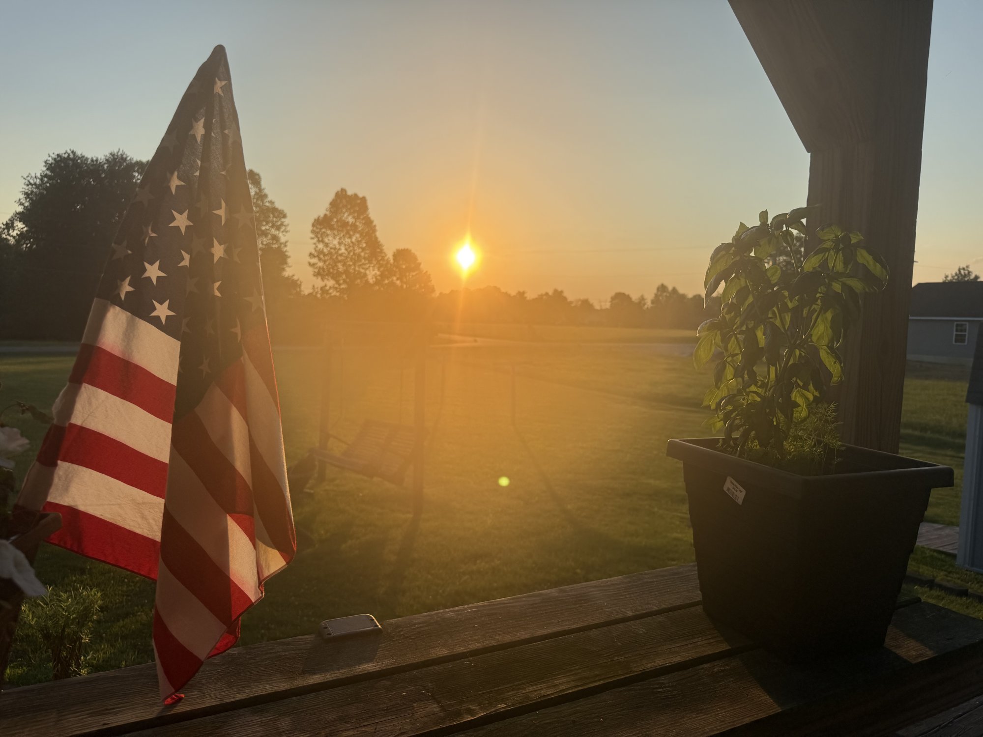 An American flag at sunrise on a porch in Ohio, photographed by Dustin Nimmo